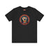 Black short-sleeve t-shirt featuring a bold embroidered design centered on the chest. The design showcases a raised fist wrapped in multicolored thread, symbolizing strength and resistance. Surrounding the fist is a circular embroidered border with intricate, colorful stitching in shades of red, orange, blue, and yellow, creating a striking contrast against the black fabric. Below the fist, the word "RESIST" is embroidered in capital letters using a gradient of warm-toned thread. The t-shirt has a classic c
